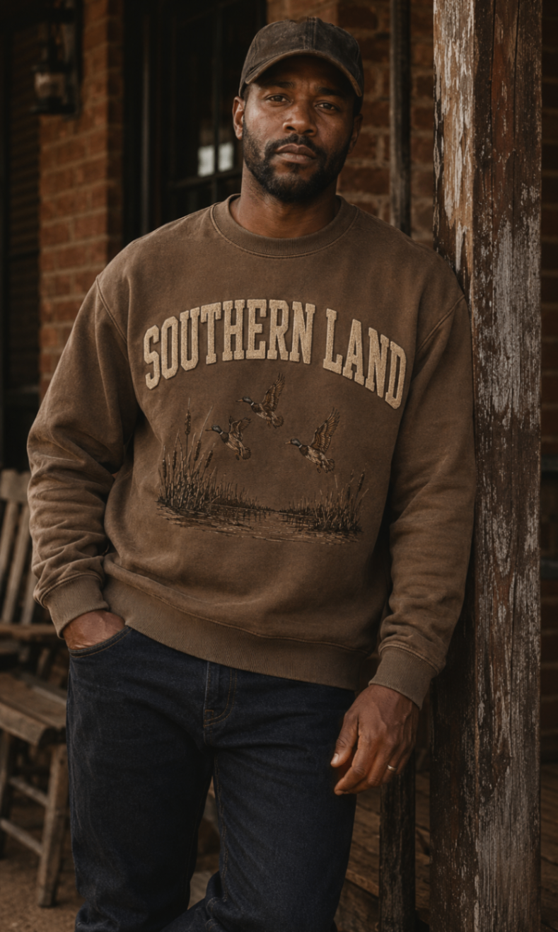 The Flight Crew crewneck worn against weathered brick on a Mississippi main street